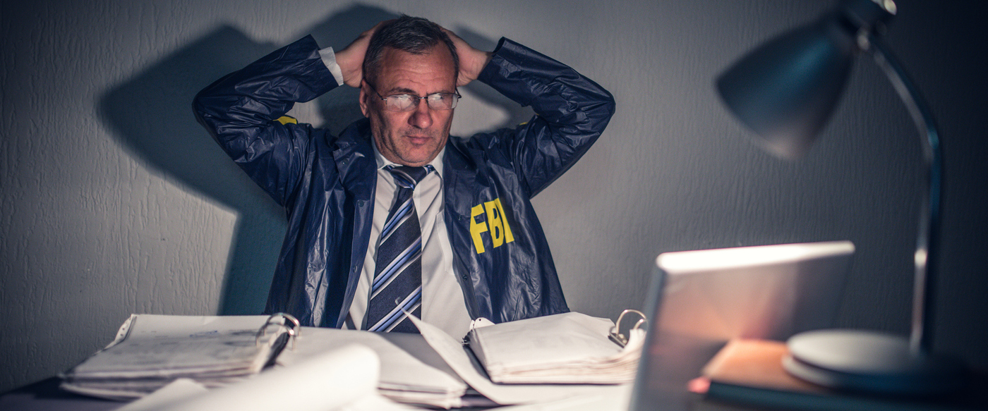 Senior FBI agent working in his office and holding his head...