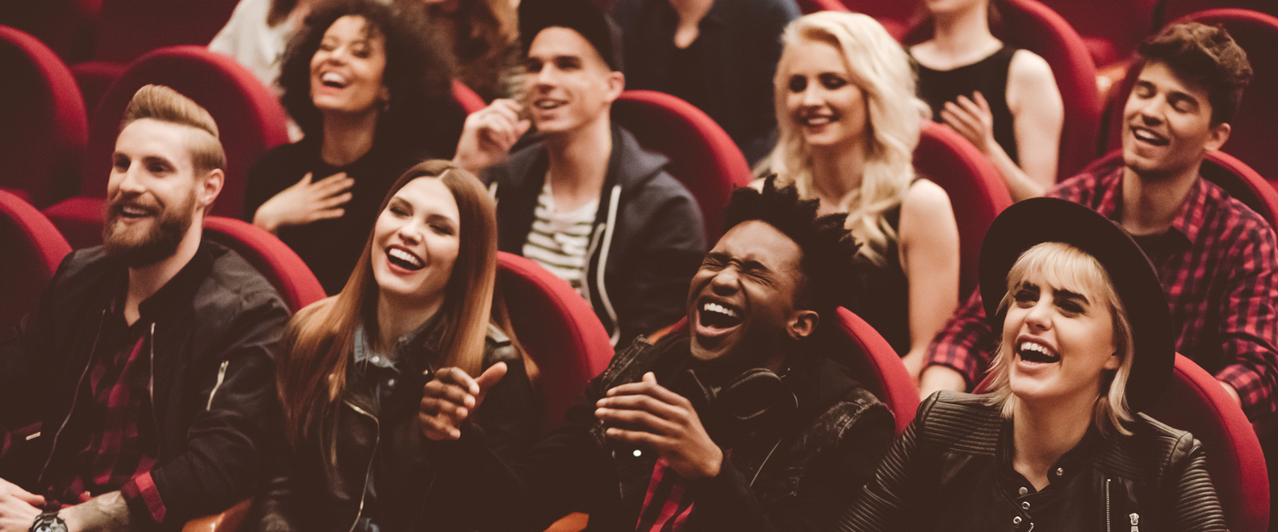 Multi ethnic group of young people in the cinema or theater, watching, laughing....